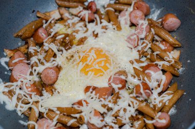 Dilimlenmiş sosisler bir yumurtayla kızartma tavasında kızartılır. Dilimlenmiş sosisler kızartma tavasında yumurta ile kızartılır..