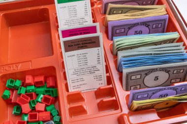 Klasik Monopoly masa oyunu, banknotları, evleri, mülk kartları ve otelleri olan bankacı kurulu
