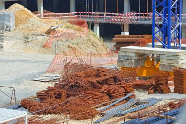 İnşaat malzemeleri ve bariyerleri olan bir inşaat alanında paslı demirler yığını