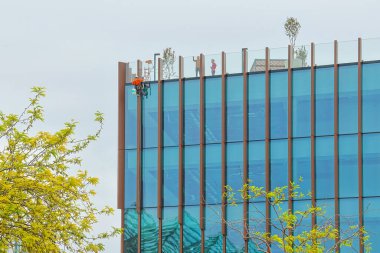 Lisbon 'daki çağdaş bir ofis binasının dışını temizleyen profesyonel bir işçi.