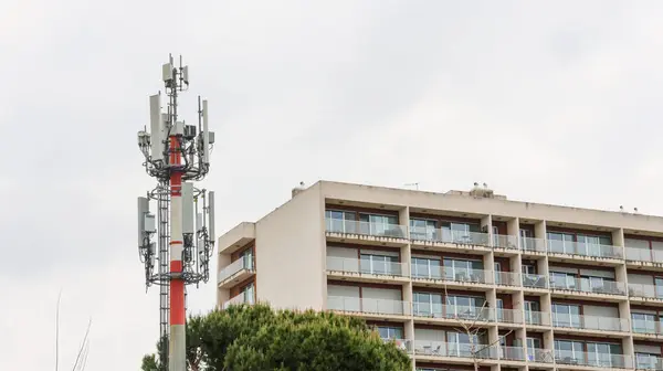 Modern baz istasyonu bulutlu bir gökyüzüne karşı dimdik ayakta duruyor, bir apartman bloğuyla çevrili.