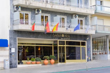 Farklı ülkelerin bayrakları ve dalgalanan bölgeleri olan bir otelin dış cephesi.