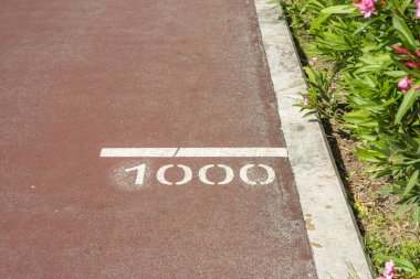 Beyaz çizgiler kırmızı koşu yolunun 1000 metre noktasını gösteriyor.