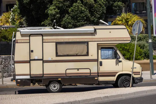Eski ve kirli bir karavan, Avrupa 'da bir caddede, ön lastiği patlamış bir şekilde yasa dışı park halinde.