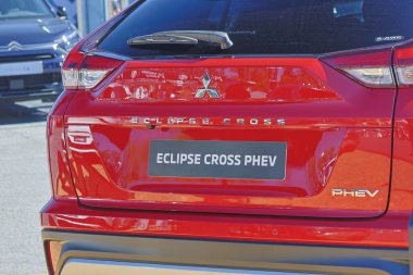 Red mitsubishi eclipse cross phev showing its logo on the back, parked in a dealership clipart