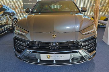 Gray lamborghini urus is parked in a modern car dealership, showcasing its sleek design and luxurious features clipart