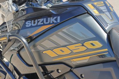 Siyah ve sarı motorsiklet yakıt tankındaki Suzuki logosunun ve modelin yakın görüntüsü.