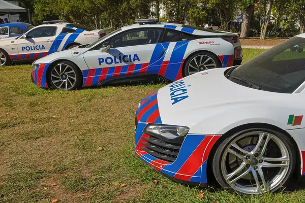 Portekiz polis arabaları otların üzerine park edilmiş, mavi ve kırmızı üniformalarını sergiliyorlar.
