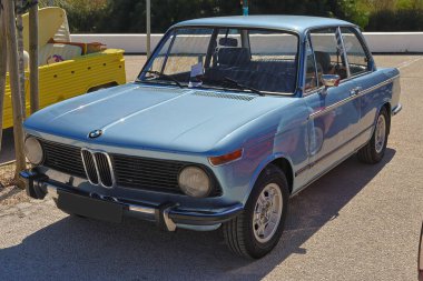 Parlak açık mavi boyalı 2002 model el değmemiş BMW kaldırıma park edilmiş.