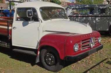 Klasik kırmızı ve beyaz borgward B1500 kamyonu, eski ihtişamına kavuştu, güneşli bir günde çimlerin üzerine park etti.