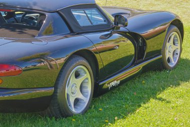 Siyah engerek karavanı çimlerin üzerine park etmiş, sağ tarafını gösteriyor.