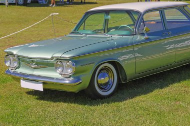 El değmemiş Chevrolet Corvair bir araba fuarında çimlerin üzerine park ederken gün ışığında parlıyor.