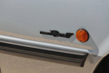 Simgesel mazda rx 7 logosu gümüş bir arabanın yanında parlıyor.