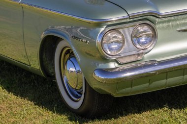 Chevrolet Corvair otların üzerine park etmiş, yakın plan farı ve lastiği gösteriyor.