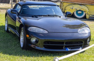 Gleaming black dodge viper rt10 convertible basking in the sun at a classic car show clipart