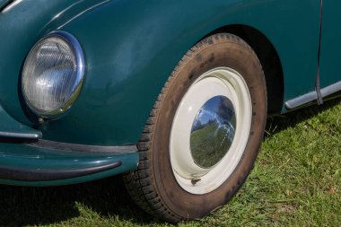 Klasik tasarım ve krom detaylarını sergileyen, çimlerin üzerine park edilmiş klasik bir sendika dkw arabasının tekerleğini kapatın.