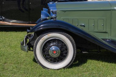 Klasik bir arabanın çim üzerindeki tekerleği, klasik tasarımını ve zarafetini sergiliyor.