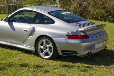 Gümüş renkli Porsche 911 turbo yeşil çimen tarlasına park edilmiş.