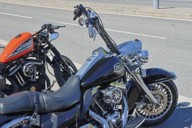 Park etmiş iki Harley Davidson motosikleti, bir yumuşak kuyruk ve güneş ışığında parlayan bir 48.