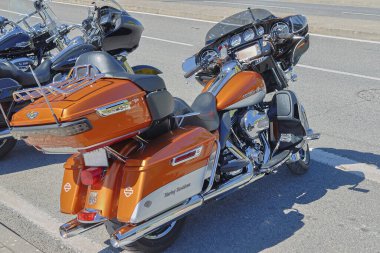 Özelleştirilmiş turuncu ve beyaz Harley Davidson elektra süzülme motosikleti asfalt yolda park halinde.