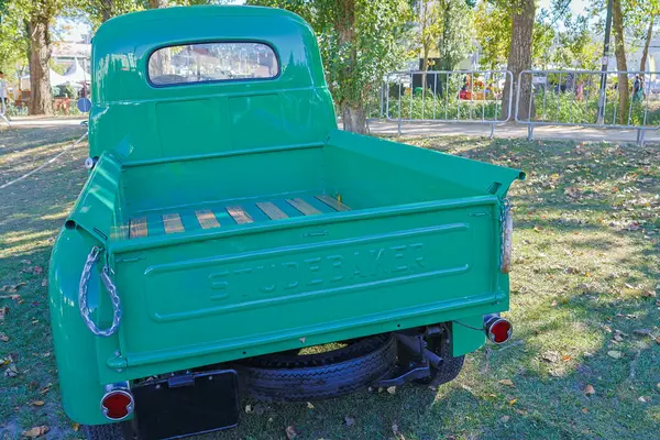 Yenilenmiş yeşil Studebaker kamyonet güneşli bir günde çimlerin üzerine park edilir.