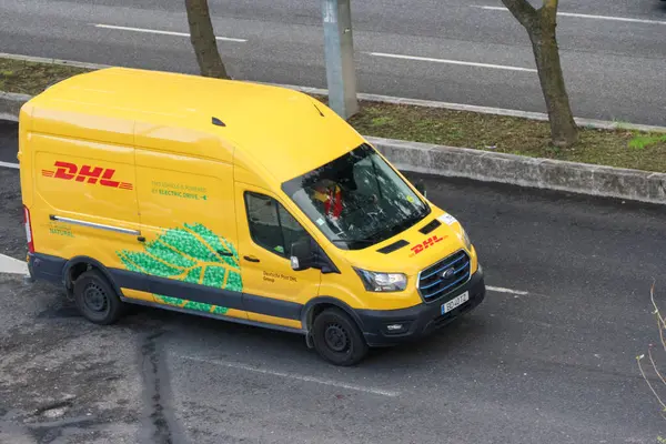 Sarı DHL Ford transit kurye elektrik dağıtım minibüsü yolda gidiyor.