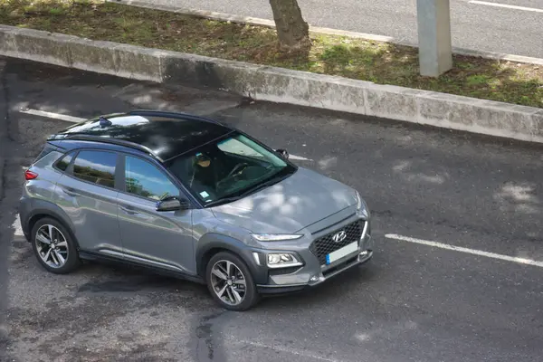 Gri Hyundai Kona. Direksiyonda şoförü var. Yolda seyahat ediyor.