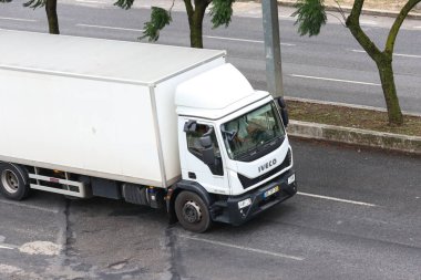 Beyaz fildişi teslimat kamyonu çok şeritli bir yolda gidiyor.