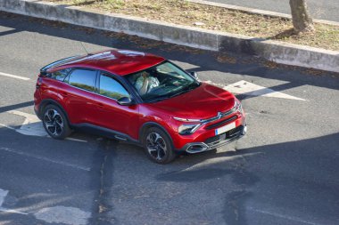 Son sınıf öğrencisi bir kadın güneşli bir günde kırmızı bir C4 kullanıyor.