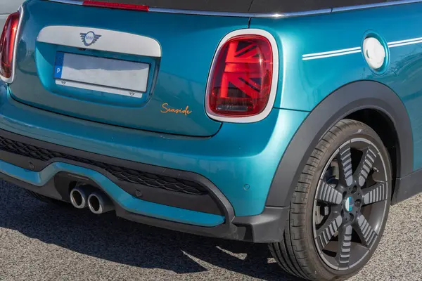Turkuaz bir Cabrio deniz kenarı baskısının arka tarafı asfalta park edilmiş.