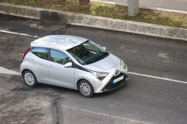 Modern gümüş toyota aygo, profesyonel bir sürücü tarafından asfalt yolda sürülüyor.