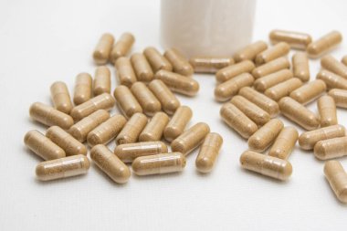 Konteynırlarından beyaz bir yüzeye sayısız bitkisel hap dökülüyor.