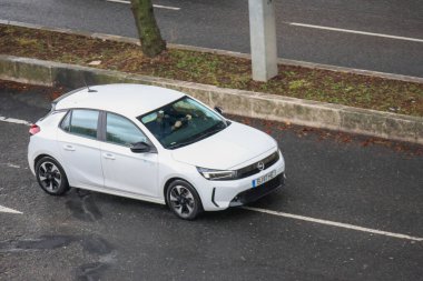 Adam çok şeritli bir yolda yeni bir beyaz Opel Corsa kullanıyor.
