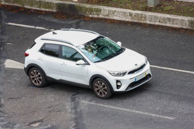 Bulutlu bir yaz gününde şehrin asfalt yolunda giden modern beyaz çapraz araba.