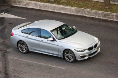 Gümüş renkli BMW 4 serisi Grand Coupe asfalt yolda ilerliyor.