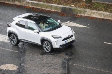 Beyaz toyota yaris haçı bulanık bir arka planla yolda gidiyor.