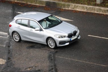 Modern gümüş renkli hatchback araba bulutlu bir günde beyaz gömlekli bir adam tarafından kullanılıyor.