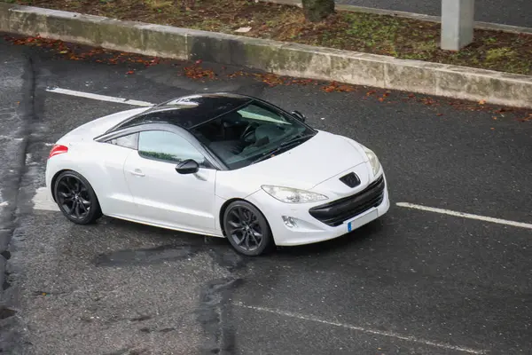 Siyah çatılı beyaz peugeot rcz asfalt bir yolda duruyor.