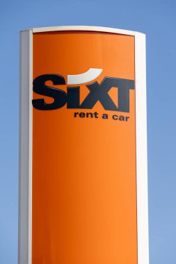 Turuncu altılı, mavi gökyüzüne karşı duran bir araba tabelası kiralıyor.