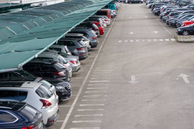 Birçok araba, güneşten korunmak için gölgelik bir yapıya sahip organize bir otoparka park etti.