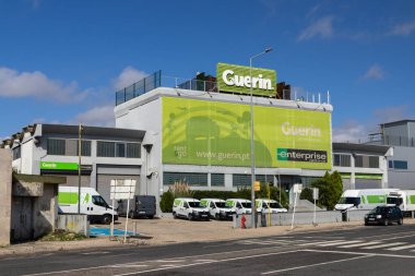 Guerin 'in dışında park etmiş beyaz minibüsler Lizbon, Portekiz' de büyük yeşil tabelası olan bir araba ofisi kiralamış.