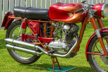 Parlak klasik ducati 250 mach 1 motosiklet çimenli bir alana park edilmiş, titizlikle muhafaza edilmiş krom ve canlı kırmızı boya sergiliyor