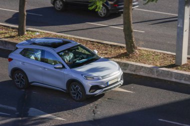 Güneşli bir yolda giden yeni gümüş renkli üçüncü perde elektrikli araba.