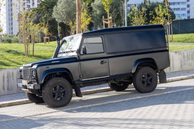 Kentsel bir ortamda parkın yakınına park etmiş özel yapım bir kara arazi gezgini savunucusu.