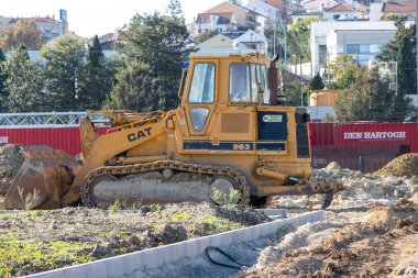 Sarı tırtıl 963 bir inşaat sahasına park etmiş, toprak taşıma işlemleri için hazır.