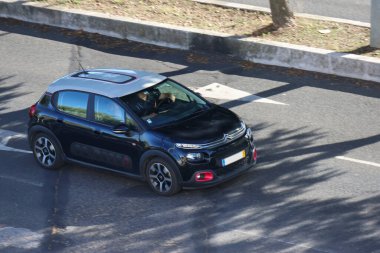 Siyah Citroen C3 güneşli bir yolda ilerliyor.