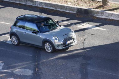 Siyah çatılı, asfalt yolda ilerleyen modern gri mini Cooper.