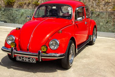 Klasik kırmızı Volkswagen böceği park halinde, zamansız tasarımını ve canlı rengini sergiliyor.