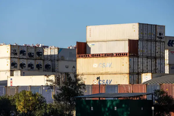 Küresel ticaret ve lojistiği temsil eden büyük metal nakliye konteynırları bir nakliye sahasında üst üste istiflendi.