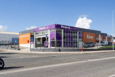 Güneşli bir günde park etmiş arabalarla modern araba kiralama binasında Viaygol markası sergileniyor.